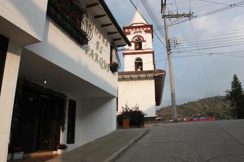 a building with a clock tower next to a street at Hotel El Parque HR in Fómeque