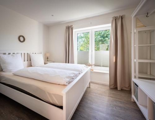 a white bedroom with a large bed and a window at Mein-Ostseeplätzchen Haus am Meer 9 in Niesgrau
