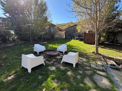 a group of white chairs and a table in a yard at Casa del Giglio a Cadelmonte in Valle