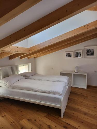 a bedroom with a white bed and wooden floors at La Casa dei Turchi in Rovereto