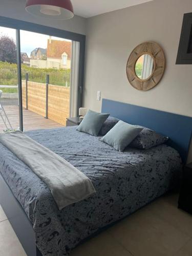 - une chambre avec un lit bleu et un miroir mural dans l'établissement Maison avec toit terrasse, à Villers-sur-Mer