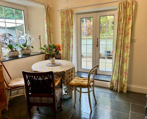 ein Esszimmer mit Tisch und Stühlen und Fenstern in der Unterkunft The old Manor House in Lifton