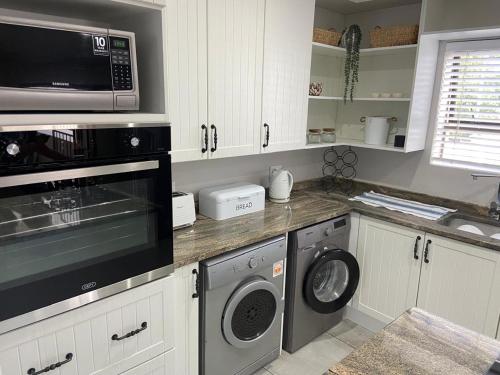 a kitchen with a microwave and a washer and dryer at 6 Elgin House in Mossel Bay