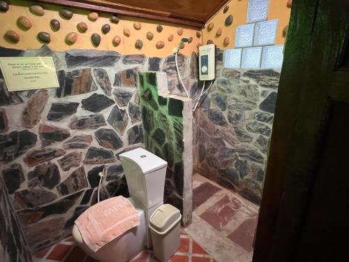 a bathroom with a stone wall and a toilet at Riverside Retreat Sukhothai Guest House in Sukhothai