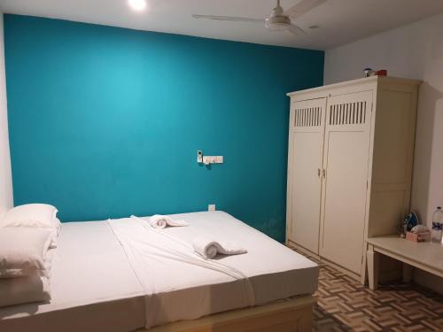 a bedroom with a blue wall and a bed at Beach Heaven Maldives - Golden Turtle Guest House in Huraa
