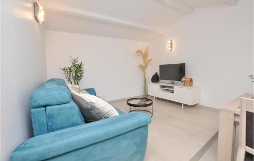 un salon avec un canapé bleu et une télévision dans l'établissement Awesome Home In Cavalaire-Sur-Mer, à Cavalaire-sur-Mer