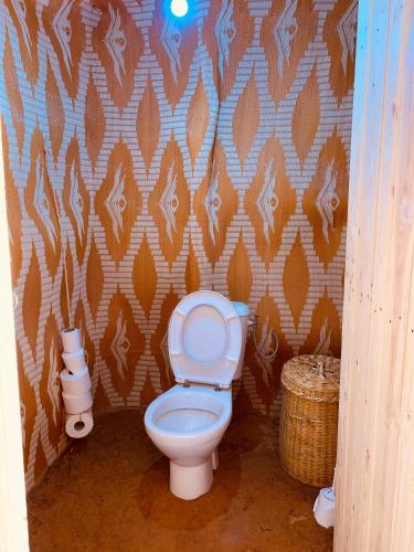 a bathroom with a toilet and a wall at Eco Merzouga luxury camp in Merzouga
