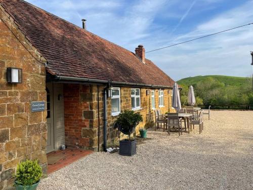 a brick house with a patio and a table and chairs at Luxury cottage with Hot Tub in Fenny Compton