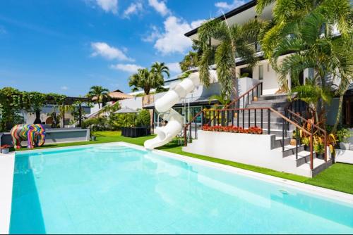 a swimming pool with a slide in front of a house at MM Villa Koh Samui in Amphoe Koh Samui