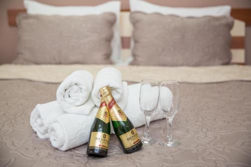 two bottles of champagne and two glasses on a bed at Sin-Kom Hotel Garni in Pirot