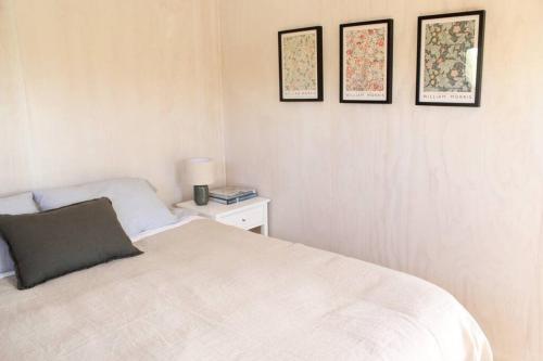 a bedroom with a bed and three pictures on the wall at Olive Grove Cabin Waipara in Waipara
