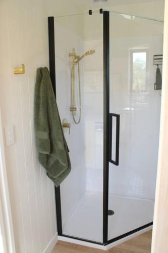 a shower with a glass door in a bathroom at Olive Grove Cabin Waipara in Waipara