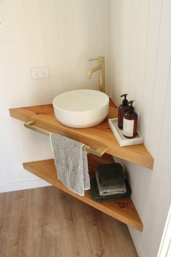 a bathroom with a bowl sink on a wooden shelf at Olive Grove Cabin Waipara in Waipara