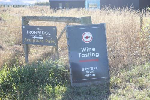 a sign for a wine tasting sign next to a fence at Olive Grove Cabin Waipara in Waipara