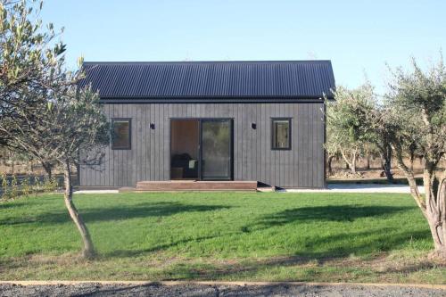 a gray house with a large yard in front of it at Olive Grove Cabin Waipara in Waipara