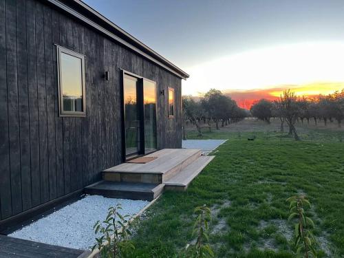 a building with a wooden ramp next to a field at Olive Grove Cabin Waipara in Waipara