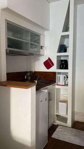 une petite cuisine avec des armoires blanches et un micro-ondes dans l'établissement Studio panthéon, à Paris