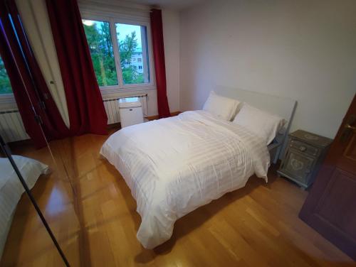 une chambre avec un lit blanc et une fenêtre dans l'établissement Cette Maison est la Vôtre, à Suresnes