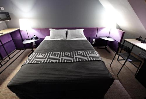 a bedroom with a large bed with purple walls and two tables at Newport in Dnipro