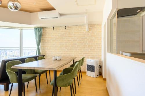 a dining room with a wooden table and green chairs at Nakajima Park stay AMS tower 27F Panoramic view of Sapporo city in Sapporo