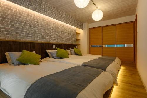 a bedroom with two beds with green pillows at Nakajima Park stay AMS tower 27F Panoramic view of Sapporo city in Sapporo