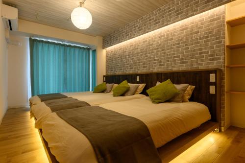a bedroom with two beds and a brick wall at Nakajima Park stay AMS tower 27F Panoramic view of Sapporo city in Sapporo