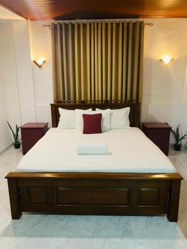 a bedroom with a large bed with a red pillow at Enara Luxury Stay in Katugastota
