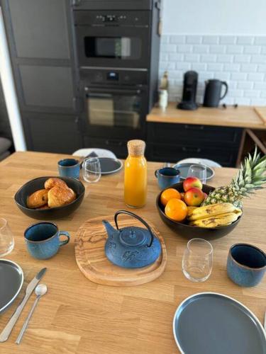 une table en bois avec des bols de fruits et de jus dans l'établissement L'Escale Maison de caractère quartier Saint Michel, à Les Sables-dʼOlonne