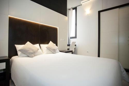 a bedroom with a large white bed with white pillows at Alhambra Suites in Madrid