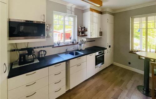 a kitchen with white cabinets and a black counter top at Gorgeous Home In Laholm With Kitchen in Laholm