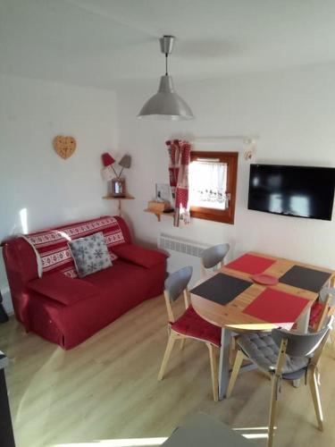 un salon avec un canapé rouge et une table dans l'établissement Charmant Studio La Toussuire, à La Toussuire