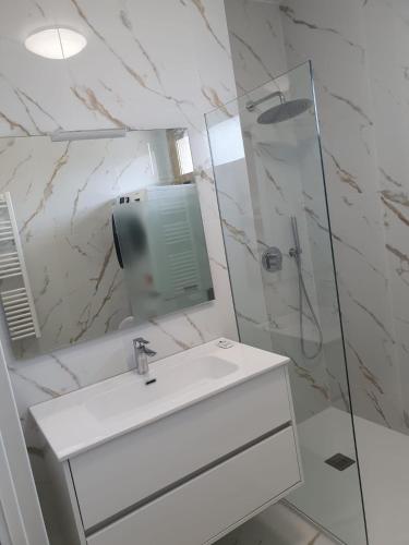 une salle de bain blanche avec un lavabo et une douche dans l'établissement T4 FRONT DE MER ,PISCINE 25 metres ,WIFI,6à8 PERSONNES,parking,GARAGE, à Roquebrune-Cap-Martin