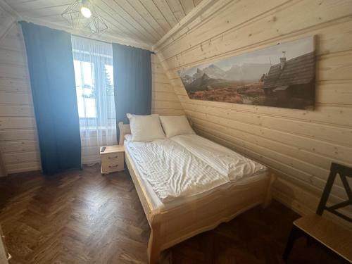 a bedroom with a bed with a painting on the wall at Apartamenty u Mocarnego in Szaflary