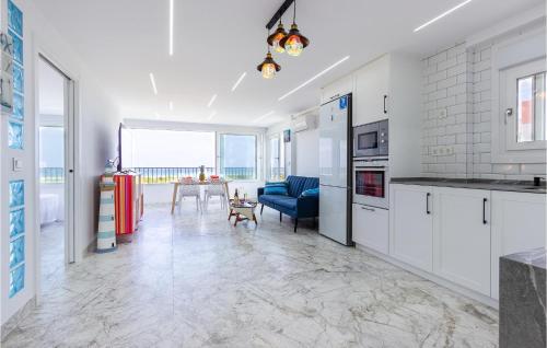 a kitchen with white cabinets and a blue couch and a table at Cozy Apartment In Guardamar Del Segura in Guardamar del Segura