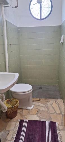 a bathroom with a toilet and a sink and a clock at Paradise Hospedaria São Thomé in São Thomé das Letras
