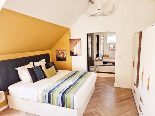 a bedroom with a large bed with a yellow wall at Seaside 3 suites Penthouse with Pool Gym & BBQ Terrace in Cap Malheureux