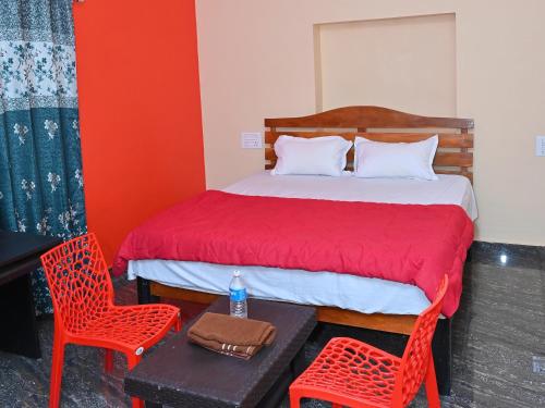 a bedroom with a bed and two red chairs at Saddharma Homestay Hampi in Hampi
