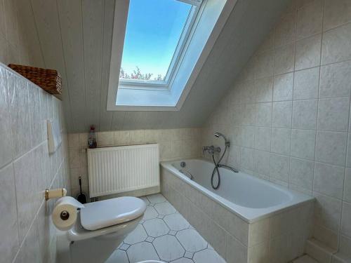 a bathroom with a toilet and a tub and a window at Bovenappartement in Winterberg met balkon en uitzicht over het bos in Winterberg