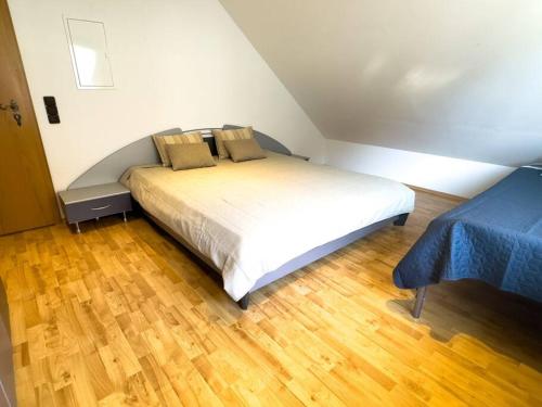 a bedroom with a white bed with a wooden floor at Bovenappartement in Winterberg met balkon en uitzicht over het bos in Winterberg