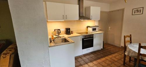 a small kitchen with white cabinets and a sink at Le Coeur Du Moulin in Saint-Aubin-le-Monial