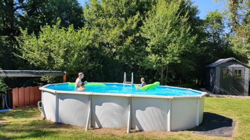 three people playing in a pool in a backyard at Le Coeur Du Moulin in Saint-Aubin-le-Monial