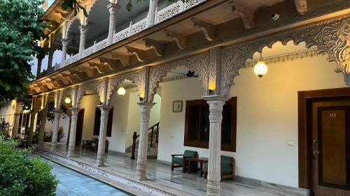 a building with columns and a hallway with tables and chairs at Hotel Sunbird in Bharatpur