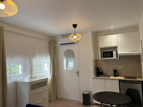 une cuisine avec des armoires blanches et une table à l'intérieur dans l'établissement Le Nid Bleu, cœur des Minimes, à Toulouse