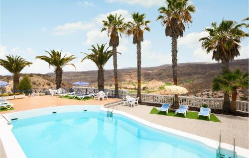 ein Pool in einem Resort mit Palmen und Stühlen in der Unterkunft Nice Home In Puerto Rico De Gran Ca in Puerto Rico de Gran Canaria