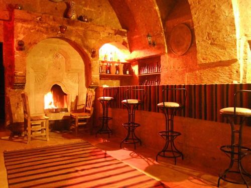 a bar with stools in a room with a fireplace at Kapadokya Ihlara Konaklari & Caves in Guzelyurt