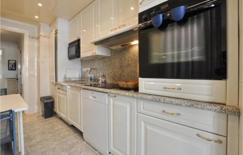 La cuisine est équipée de placards blancs et d'un grand four micro-ondes. dans l'établissement 1 Bedroom Awesome Apartment In Cannes, à Cannes