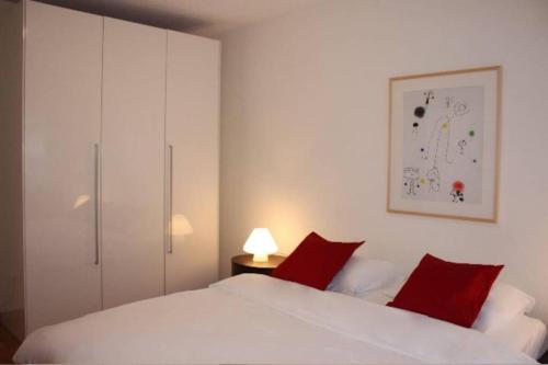 a bedroom with a white bed with red pillows at Executive 2 BD flat in city center - Hösch 1 in Zürich