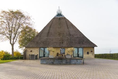 a building with a thatched roof with two chairs in front at Oppe Klincke in Franeker