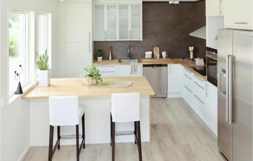 a kitchen with white cabinets and a wooden island with white chairs at Gorgeous Home In Lammhult in Lammhult