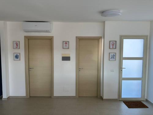 a hallway with three doors and pictures on the wall at Le Terrazze della dolce casa - Blue Sky - Casa Vacanze a Marina di Ragusa in Marina di Ragusa